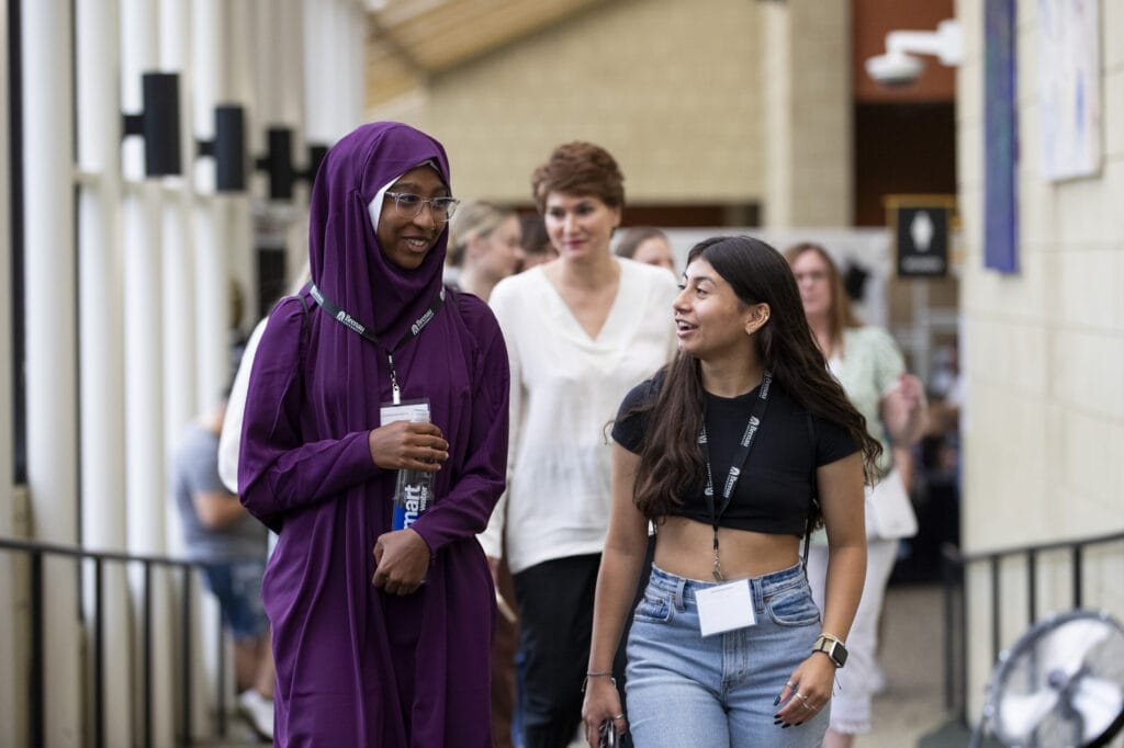 Two female students walk and talk during registration.