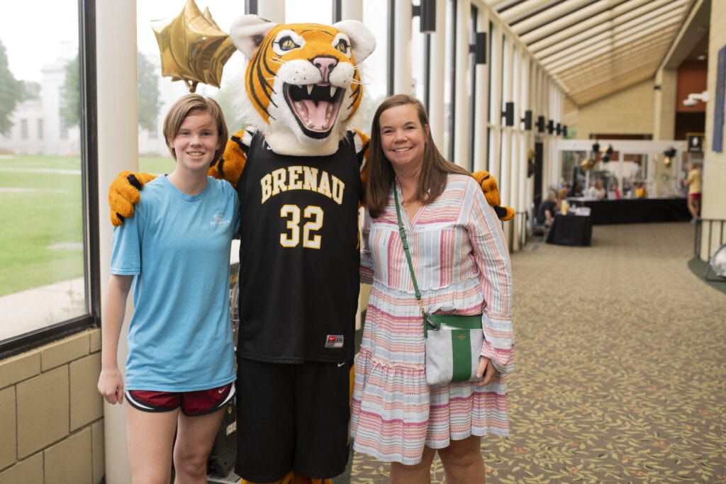 A new student and their mother pose with HJ, the Golden Tiger mascot.