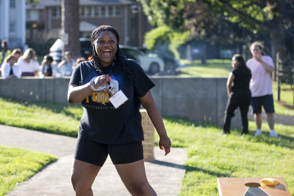 A new student smiles while playing cornhole