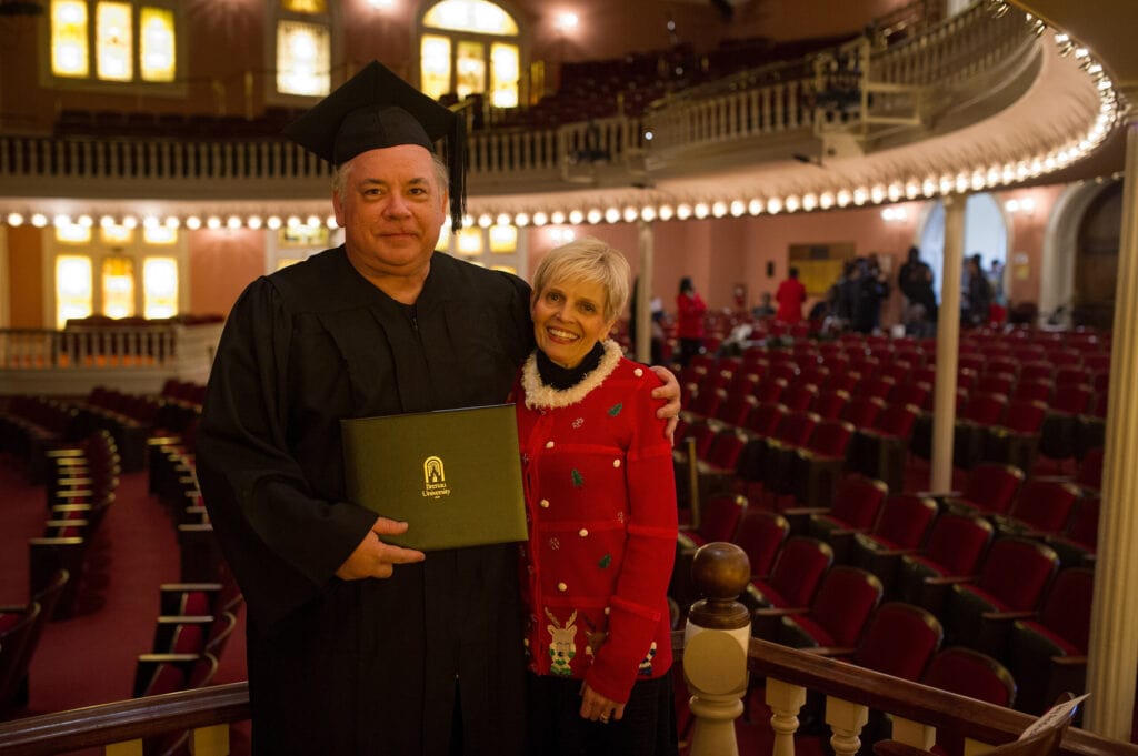 Jay Andrews, in his cap and gown, with his wife, Gigi Andrews in 2016.