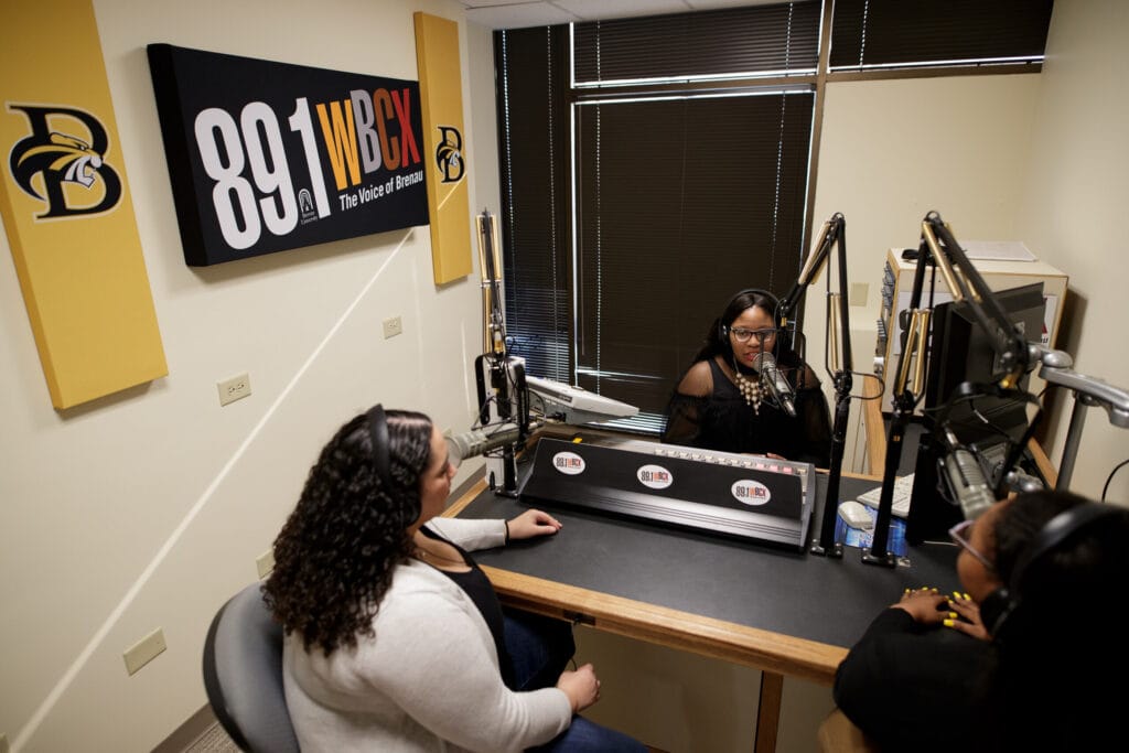 Three female students record a production in the WBCX studio in 2019.
