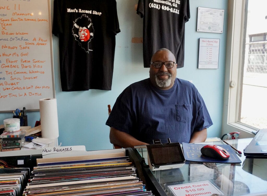 Moe Lyons sits behind the counter at his record shop.