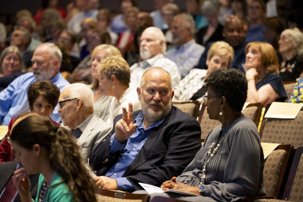 Audience members talk before lecture begins