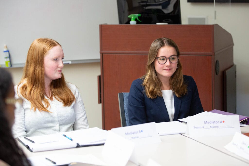 Two female students sitting together during a mediation round.