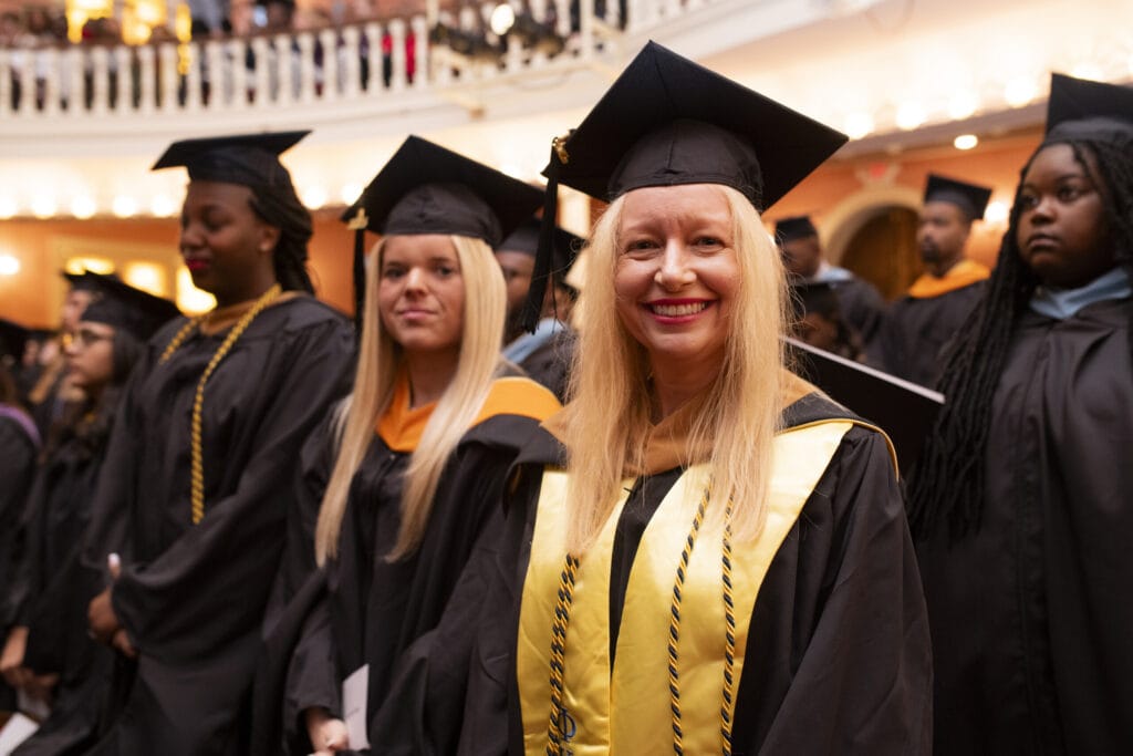 Smiling graduates waiting to walk across the stage