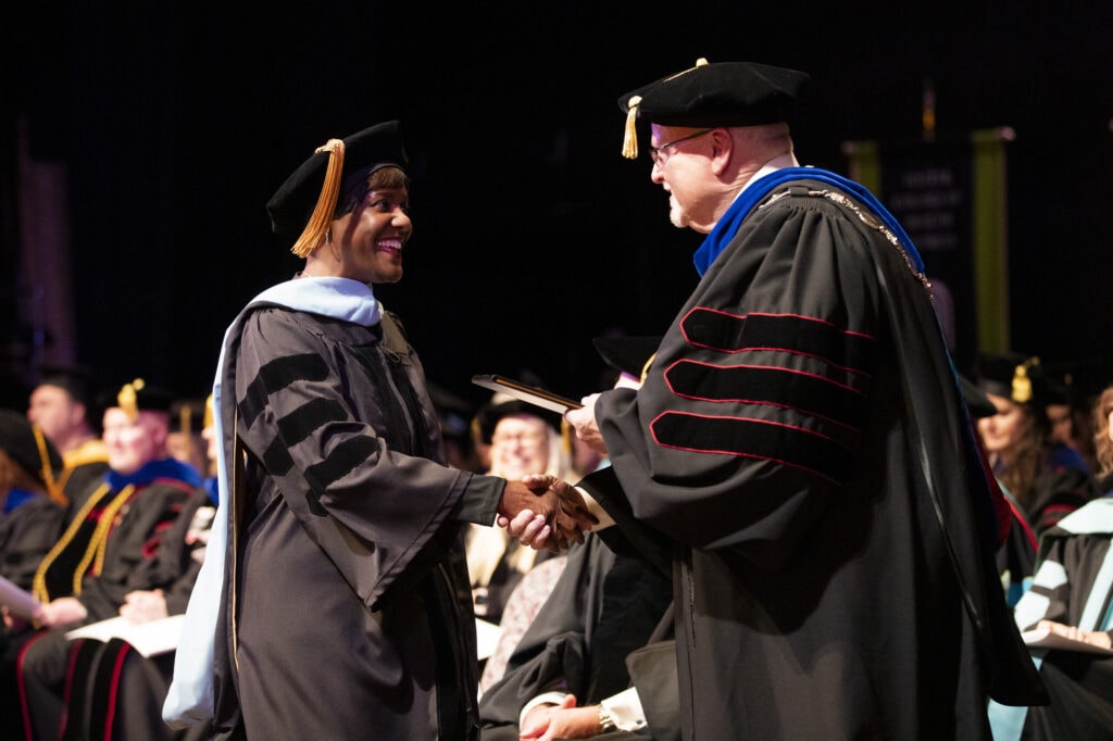 A graduate receives her diploma from Dr. Barnett