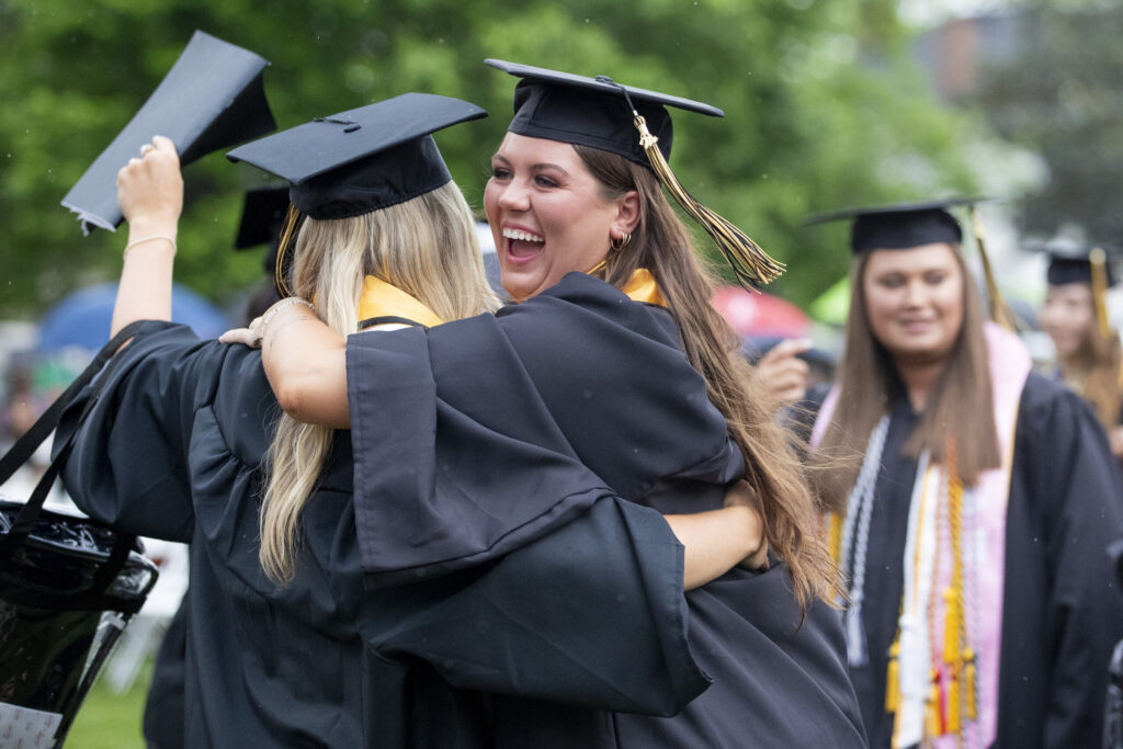 Women's College graduates hug each other on the front lawn after the 145th commencement