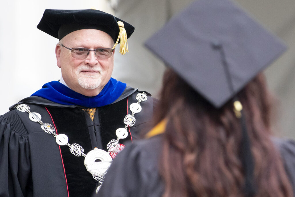 Dr. David Barnett hands a diploma to an undergraduate.