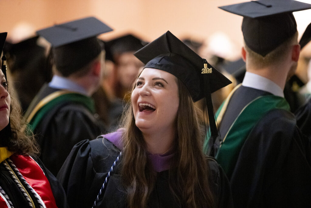 A master's degree graduate smiles at her friends and family during the ceremony.