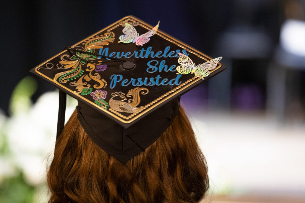 A graduate's decorated cap reading "Nevertheless, she persisted."
