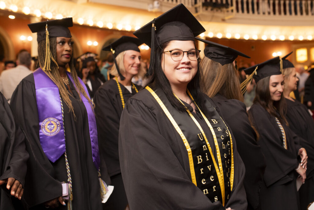 A graduate smiles before the undergraduate ceremony