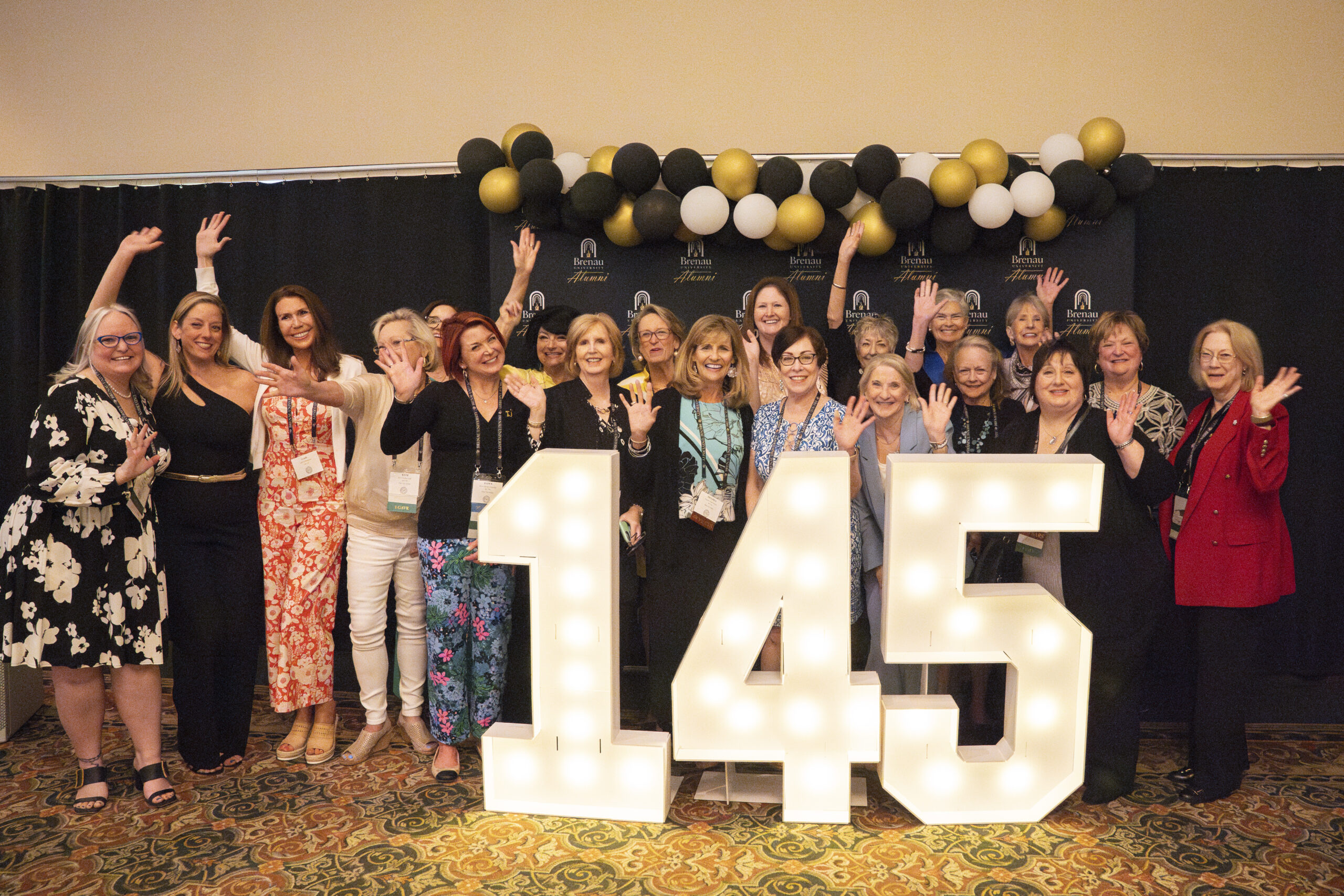 Alumni posing for a photo in front of giant numbers 145