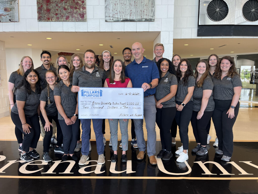 The Moultrie PT students with Benchmark staff holding a large check. Benchmark donated funds for the annual service trip.