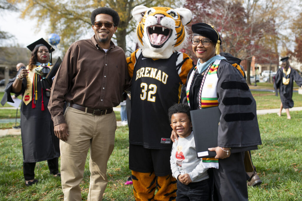 A graduate and family pose with HJ, the tige mascot