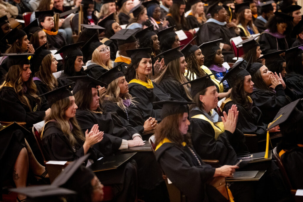 The graduates hold their degrees in the audience