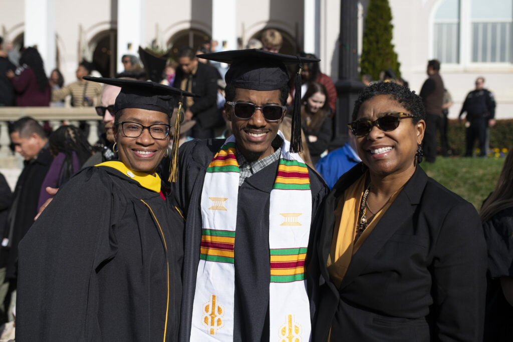 A graduate with his mother and a faculty member