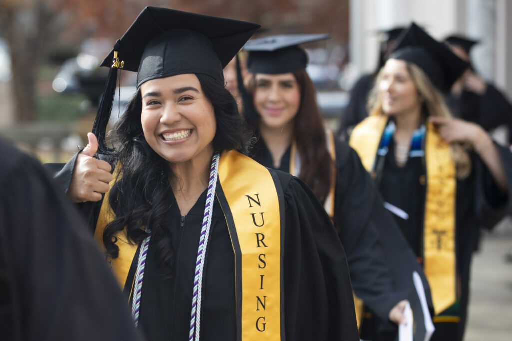 a nursing graduate gives a thumbs up while in line