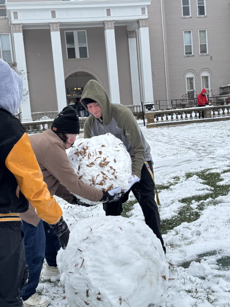 students building a snowman during the winter weather