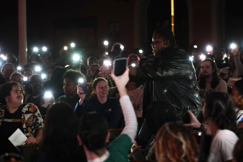 Students with their phone flashlights out welcoming the student emcee