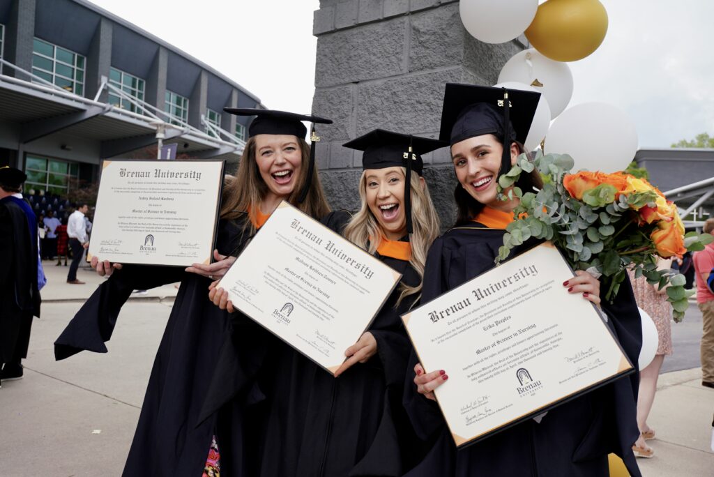 three students pose with their degrees