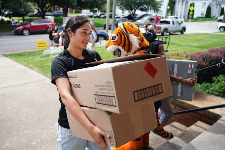 a student carries boxes into a dorm