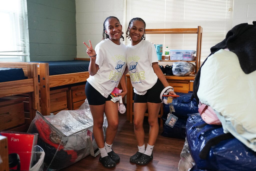 twin female students pose in their dorm room