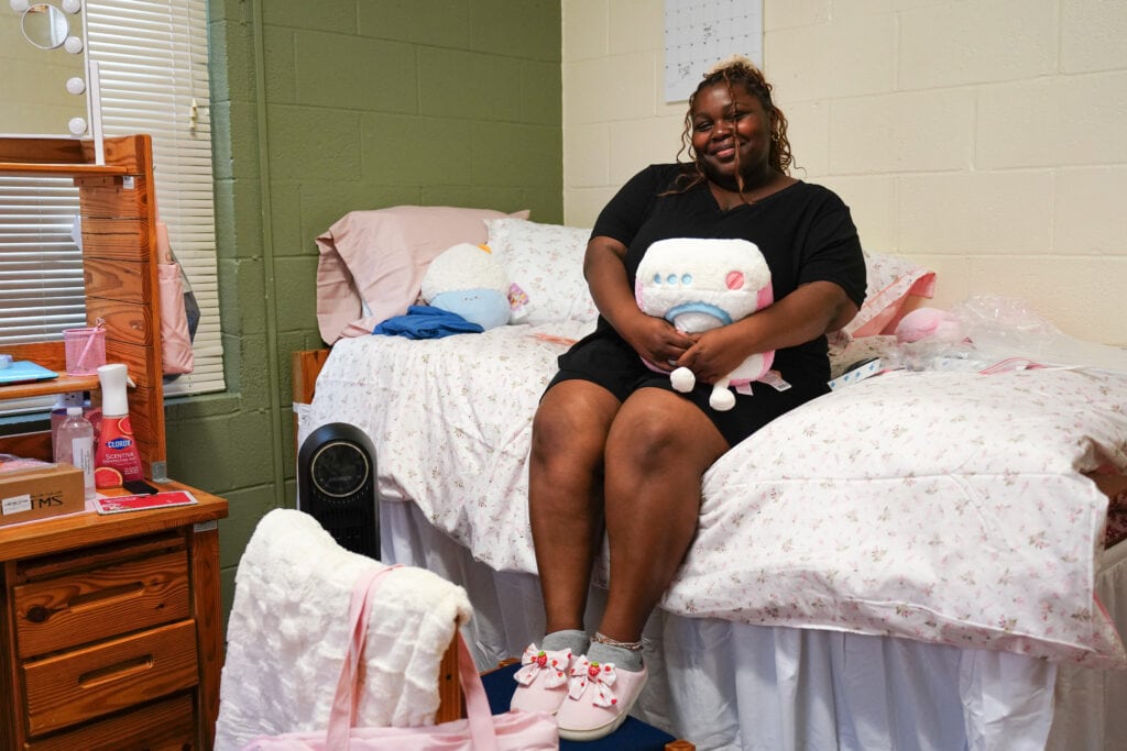 freshman female student sits on bed with stuffed animal