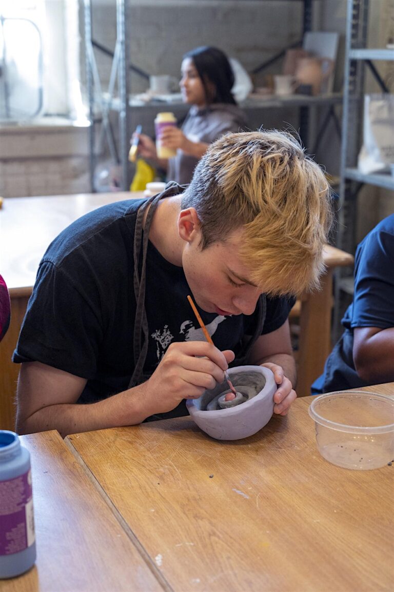 student works on pottery