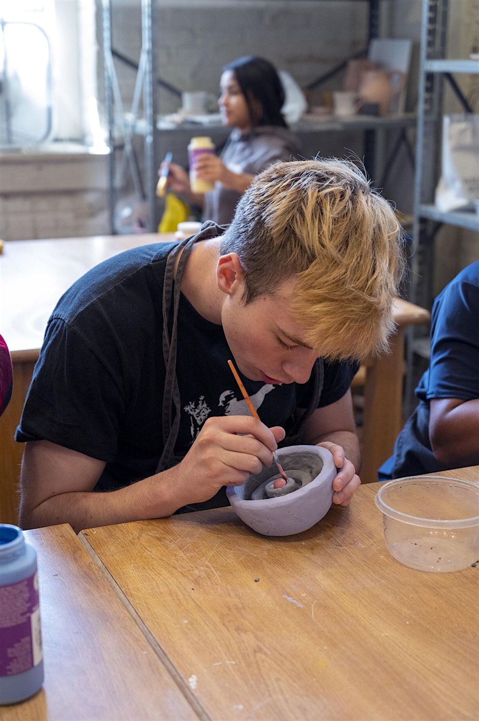 student works on pottery