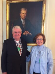 Portrait of two adults standing in front of a large framed painting at Brenau University campus.