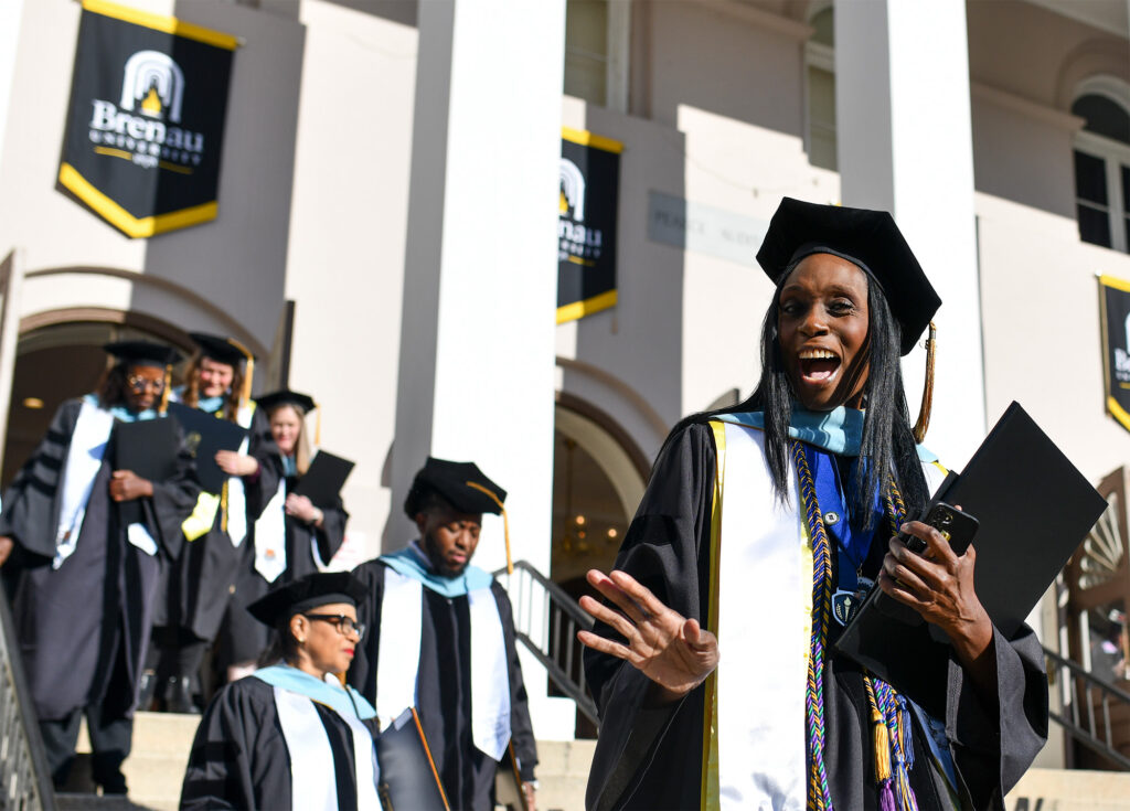 a graduate waves on the way out of the ceremony