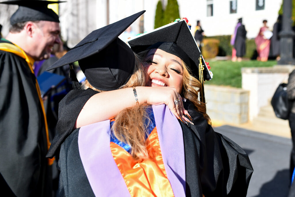 two graduates hug