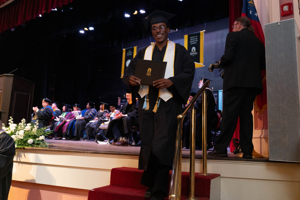 a master's graduate walks down the stairs with his diploma