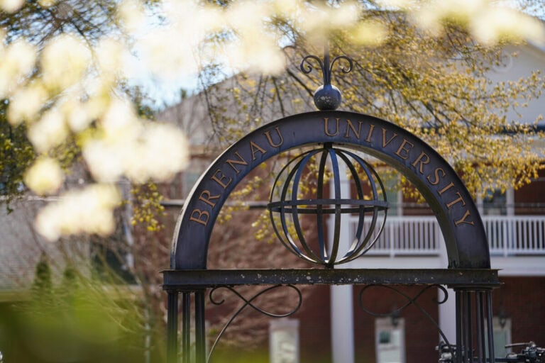 Brenau University entrance gate with campus grounds and building in background.
