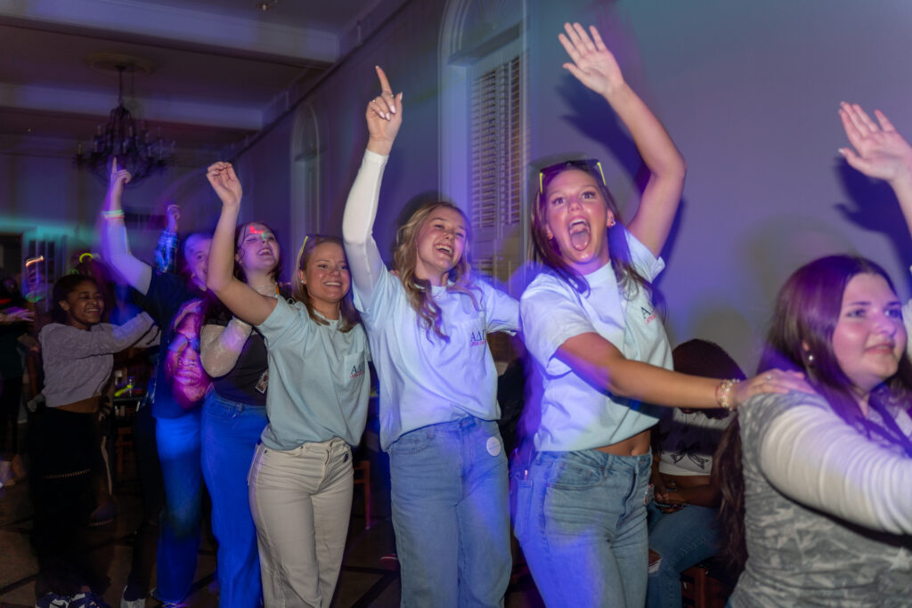 Students in a line dancing and raising one arm