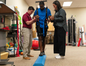 two people assist a third person with physical therapy