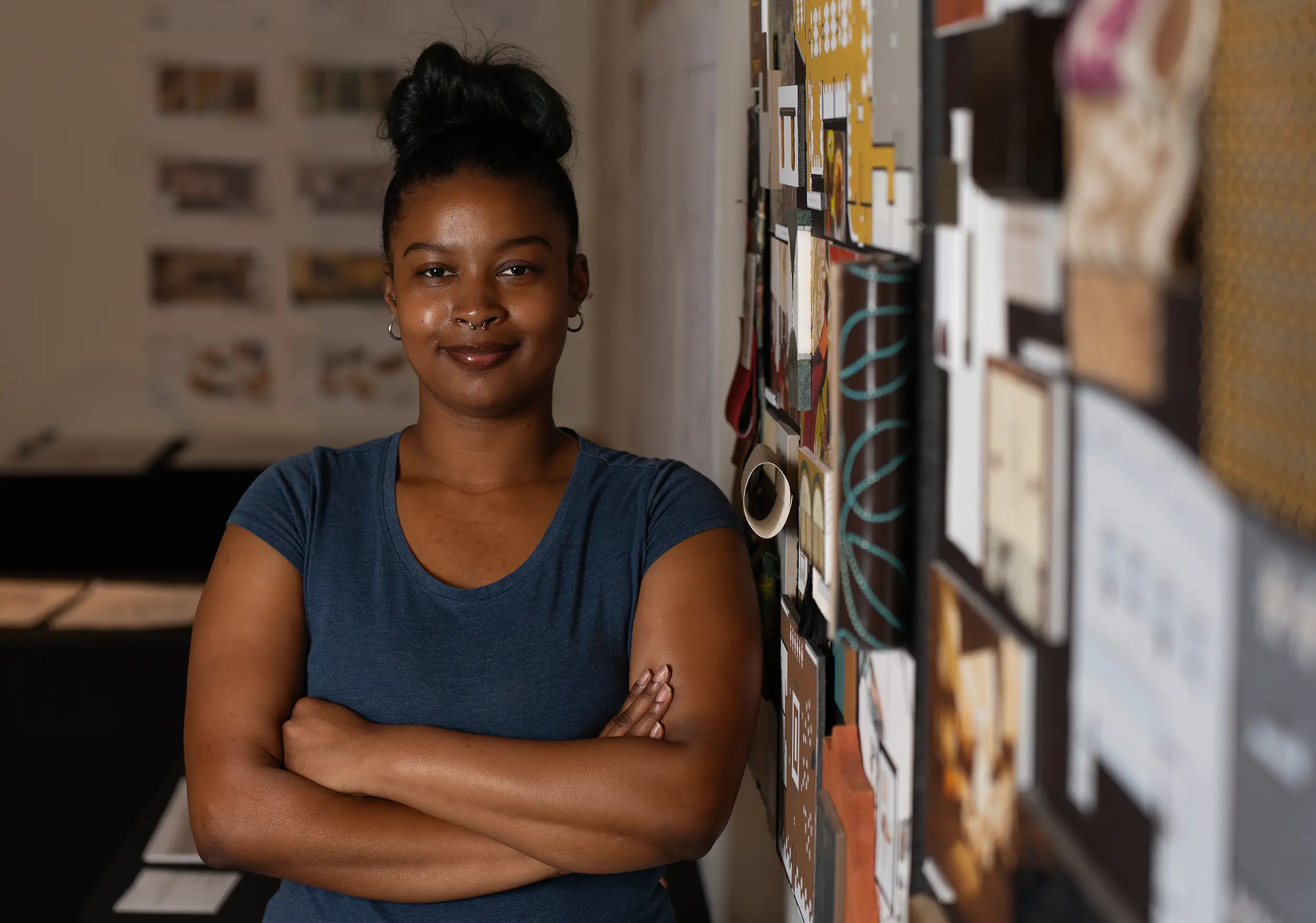 Interior design student stands beside panel of work.