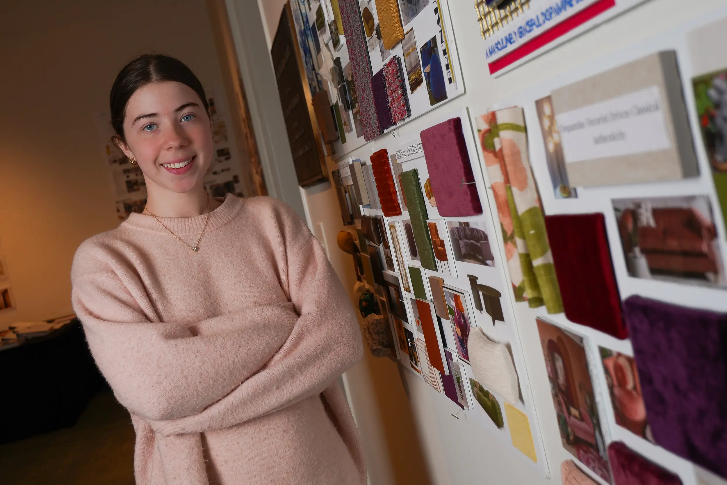 Interior design student stands beside vision board.