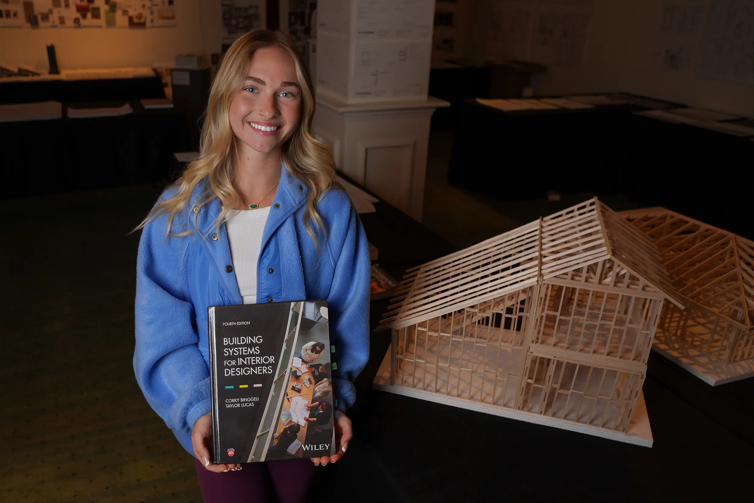 Interior design student holds textbook.