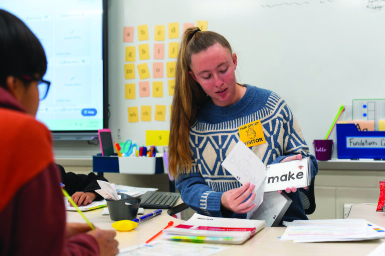 Brenau student in a classroom showing materials to students.
