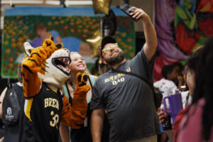 a female student and her father pose with university Tiger mascot