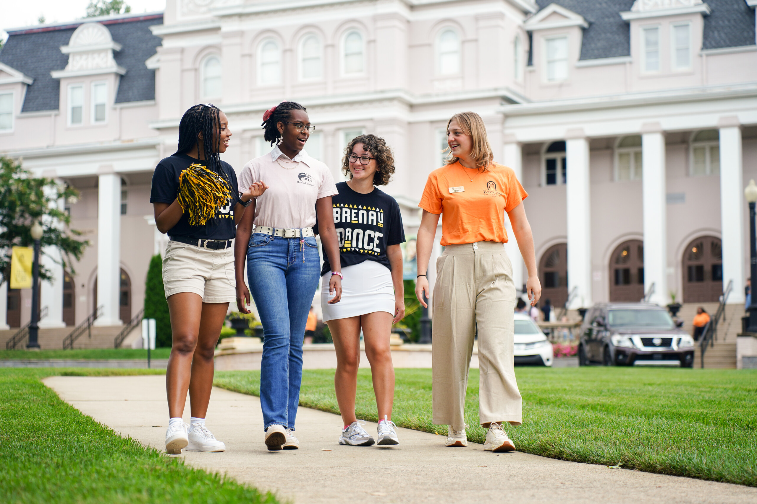 Group of students in casual attire in front of a large college building