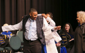 A doctoral student receives his coat during the PsyD white coat ceremony.