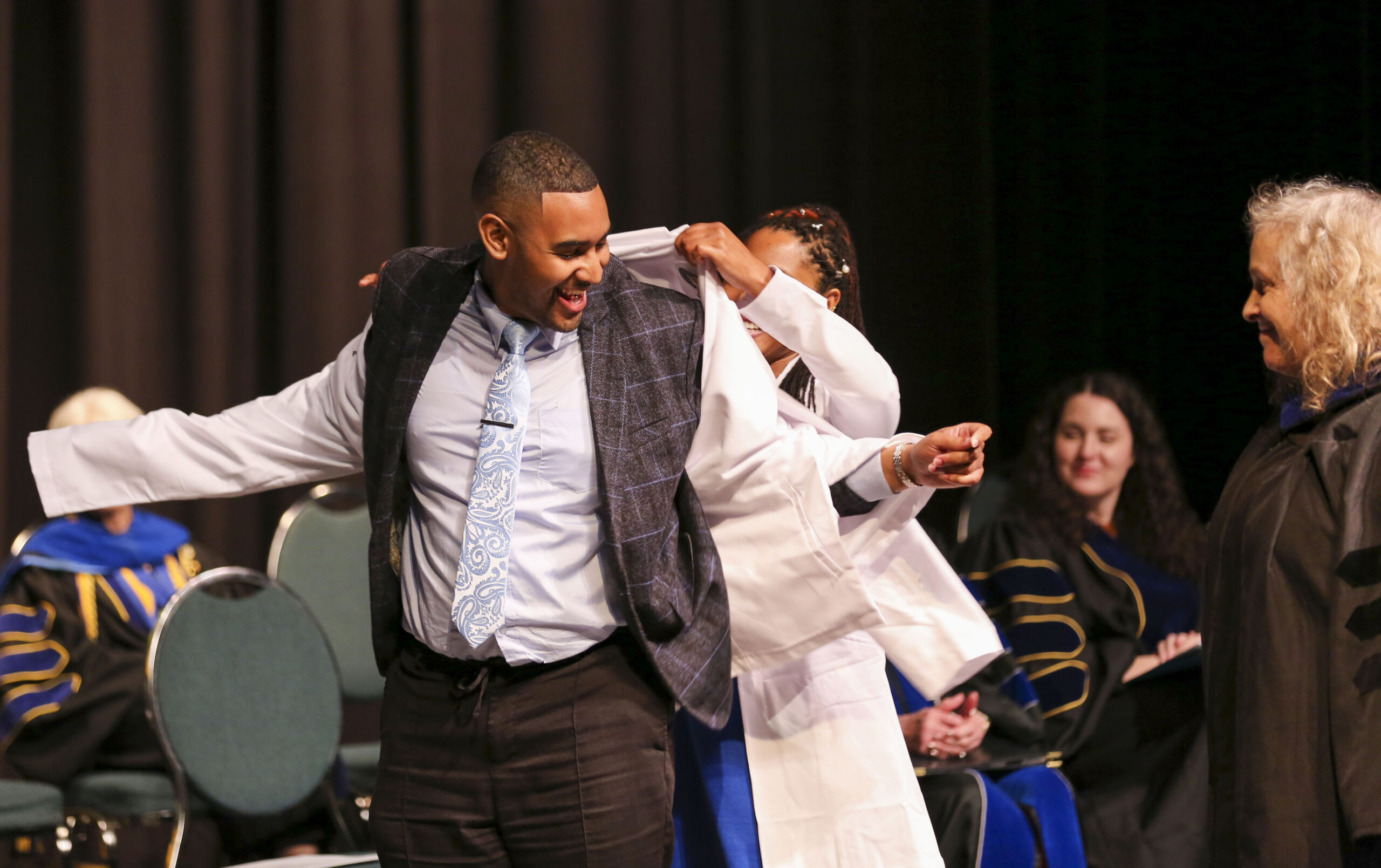 A doctoral student receives his coat during the PsyD white coat ceremony.
